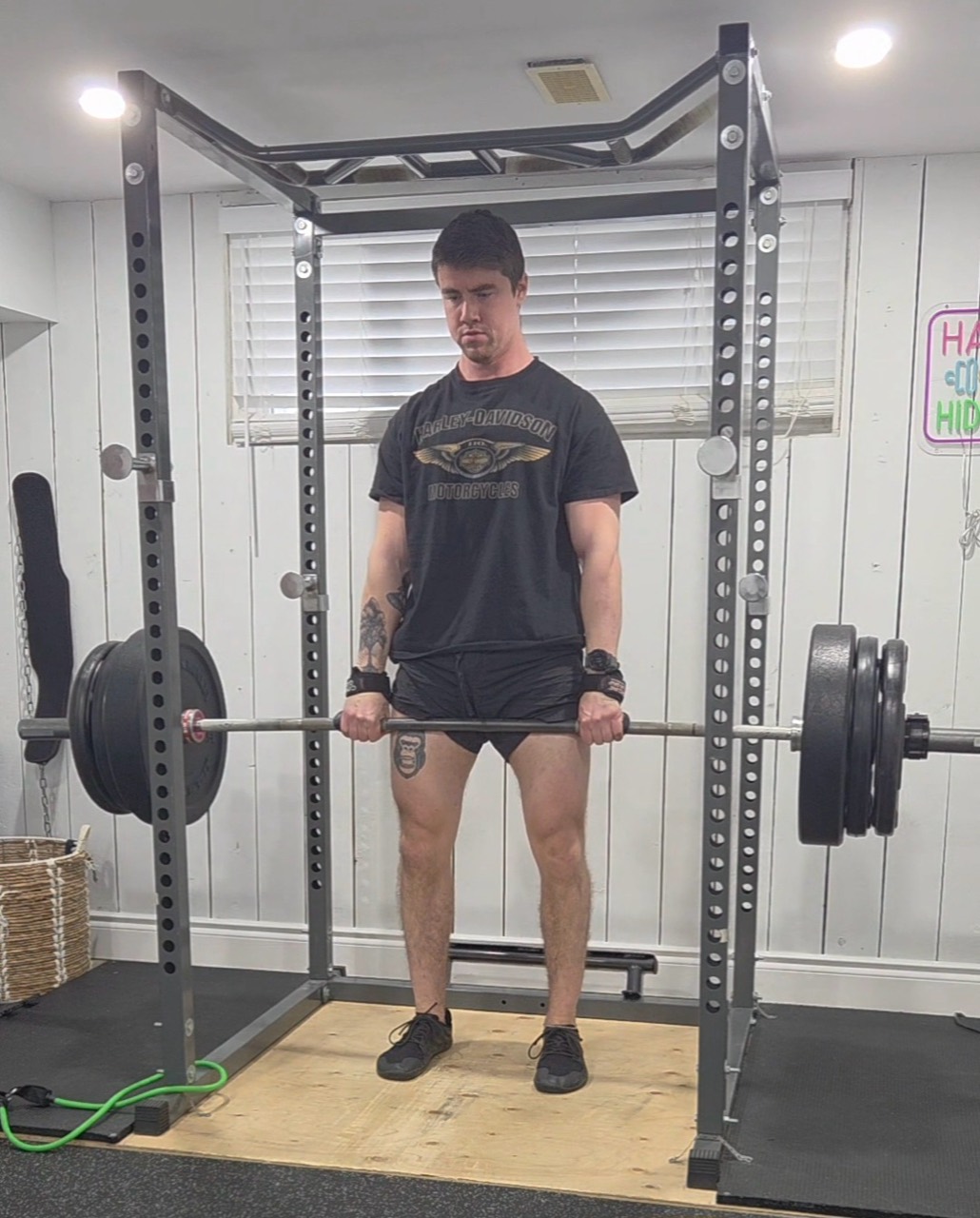 Tyler holding a loaded barbell at the top of a deadlift in his home gym